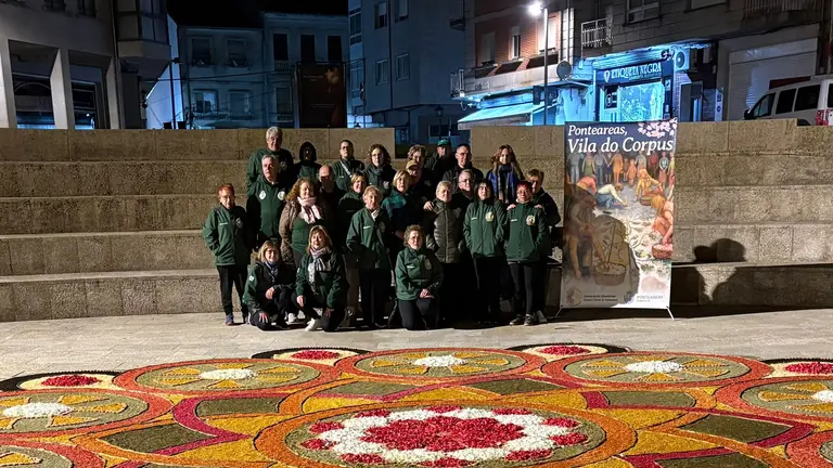 Integrantes de la Asociaci&oacute;n de Alfombristas do Corpus Christi de Ponteareas posan junto a la alfombra floral realizada en la Plaza de San Ram&oacute;n, en O Carballi&ntilde;o.