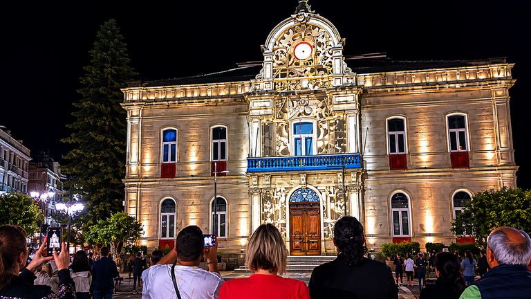Vecinos y visitantes siguen la proyecci&oacute;n art&iacute;stica sobre el hist&oacute;rico edificio consistorial de Ponteareas durante una concurrida velada nocturna. A. OUTERELO.