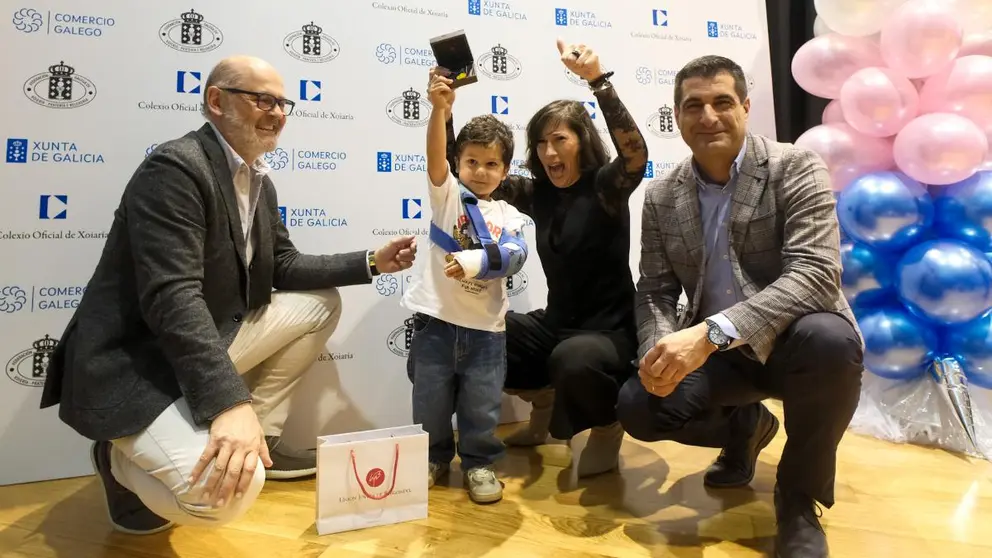 Un ni&ntilde;o celebra su premio junto a representantes institucionales durante el acto celebrado en Santiago de Compostela.