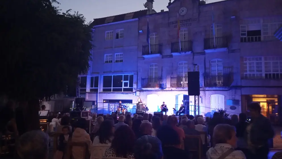 O p&uacute;blico enche a Praza do Mestre Cervi&ntilde;o para asistir ao concerto de Mar&iacute;a do Ceo, coa Casa do Concello de Covelo como pano de fondo.