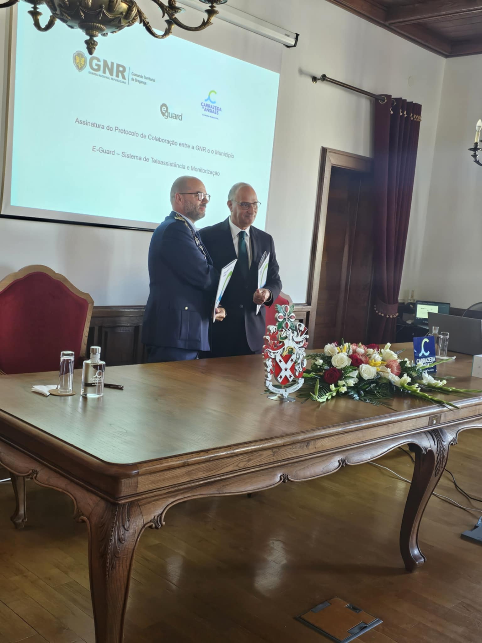 Projeto Eguard_ CZA (1)O Presidente da Câmara de Carrazeda de Ansiães, João Gonçalves, e o Comandante Territorial de Bragança da GNR, Coronel Lobo de Carvalho, formalizam o protocolo para o projeto E-Guard, uma iniciativa que reforça o apoio aos idosos mais vulneráveis do concelho.