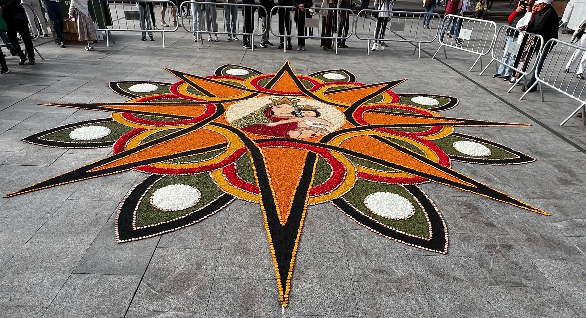 El arte efímero que espera a la Virgen: Detalle del corazón de la alfombra con la imagen de la Virgen y las franjas entrelazadas (roja y amarilla).
