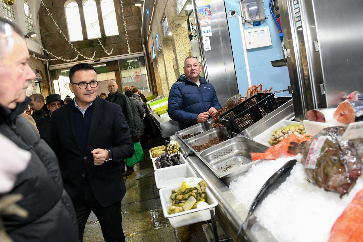 El conselleiro de Emprego, Comercio e Emigración, José González, recorre los puestos de la Plaza de Abastos de Santiago durante la presentación del programa Plato de Mercado.