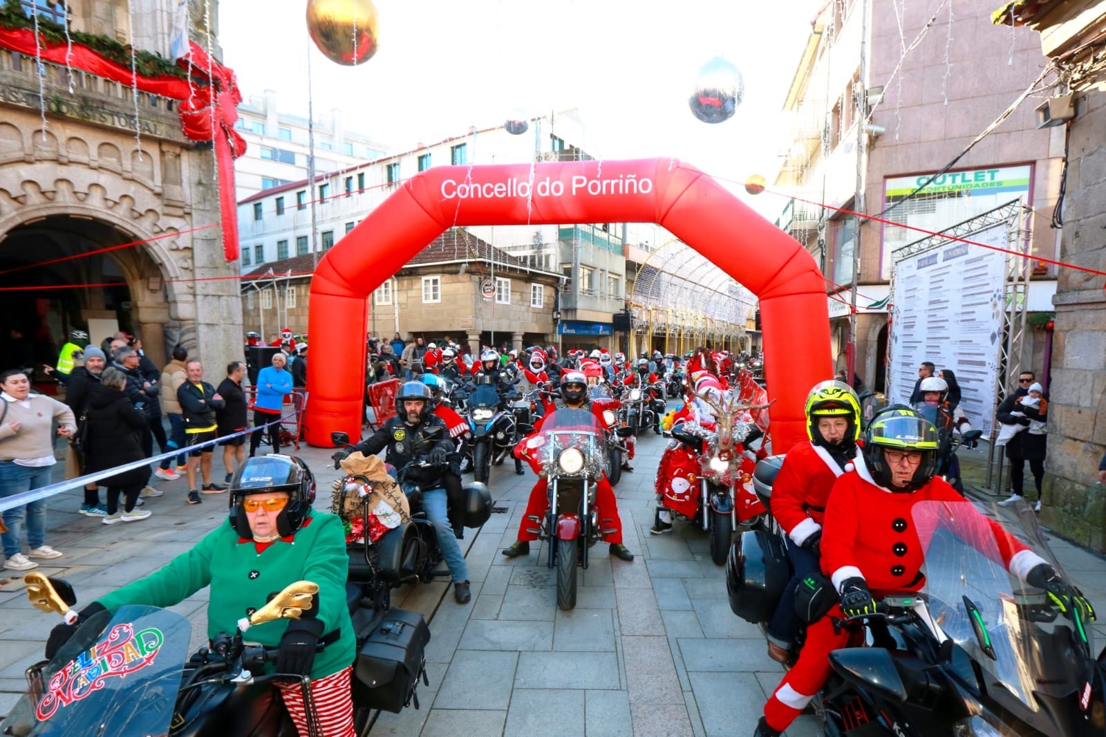 comitiva sobre dúas rodas atravesa o arco do Concello do Porriño no inicio do percorrido urbano, nunha cita navideña marcada polo ambiente festivo e familiar.