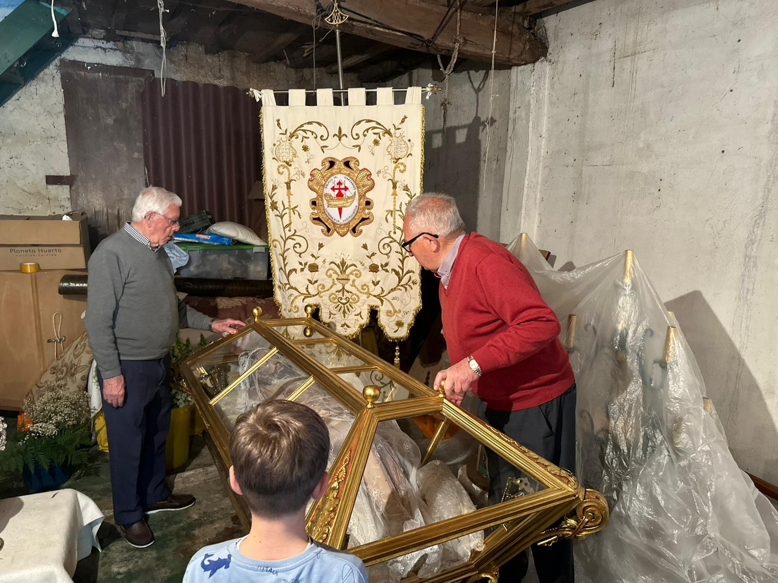 Vecinos trabajan en la preparación del Cristo de la Urna en el interior de la Casa de Novenas, uno de los momentos clave previos a la Semana Santa de Cangas.