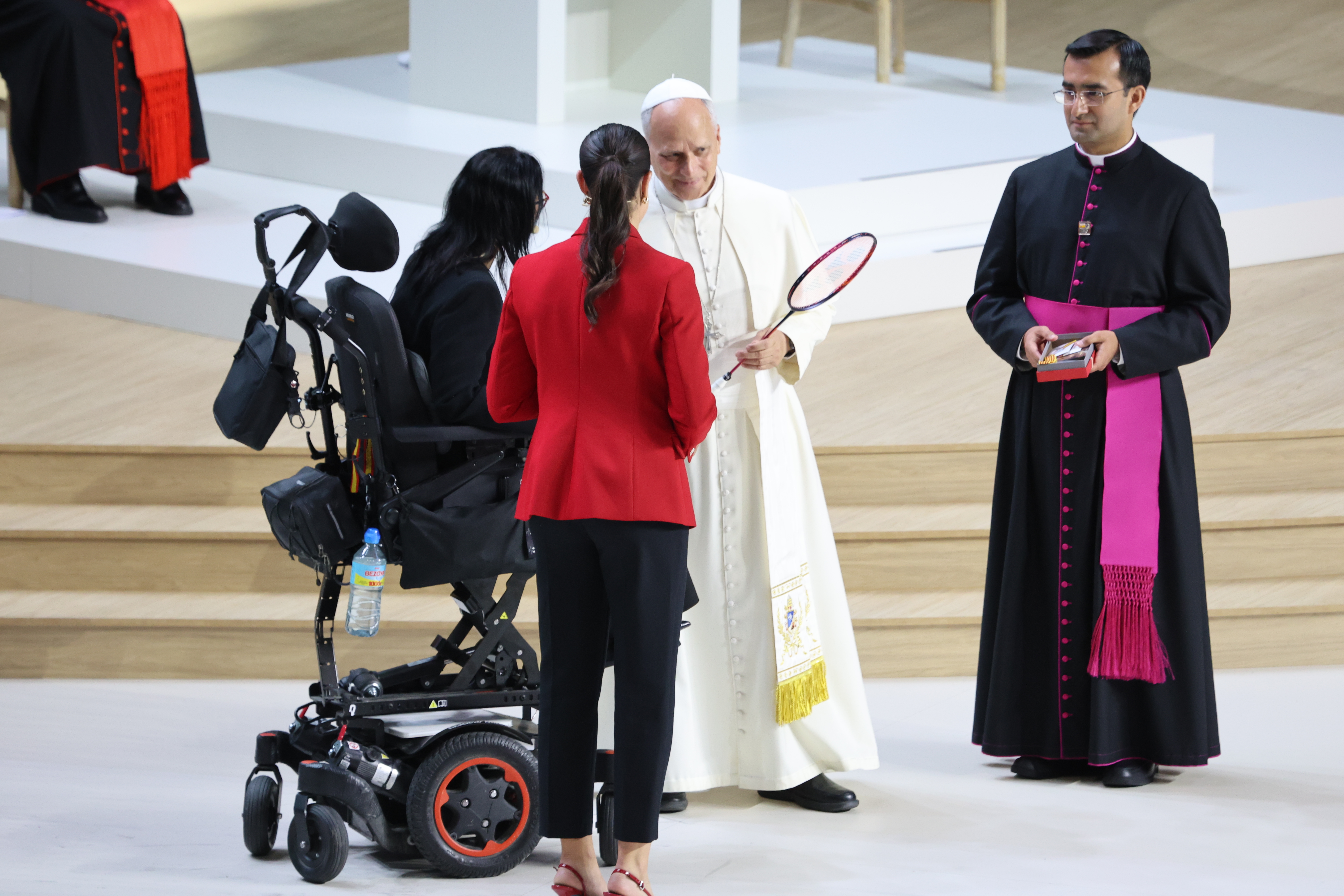 Carolina Marín entrega una raqueta al Santo Padre durante el encuentro «Tejer Redes», celebrado en el Movistar Arena de Madrid, mientras Teresa Perales acompaña el emotivo momento. GABRIEL GONZÁLEZ-ANDRÍO.