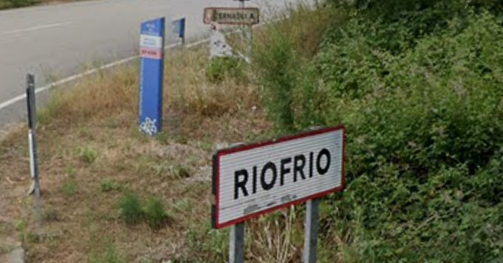 Cartel de entrada a Riofrío, coa ponte de Cernadela ao fondo, un dos símbolos patrimoniais máis recoñecibles da parroquia.