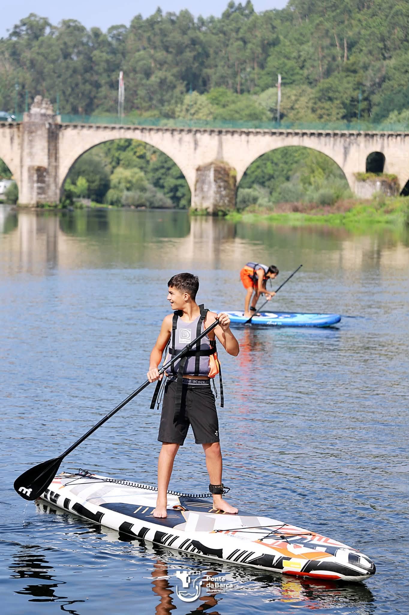 Jóvenes participantes practican paddle surf en la zona ribereña de Ponte da Barca, una de las actividades incluidas en el programa de Barca Jovem.