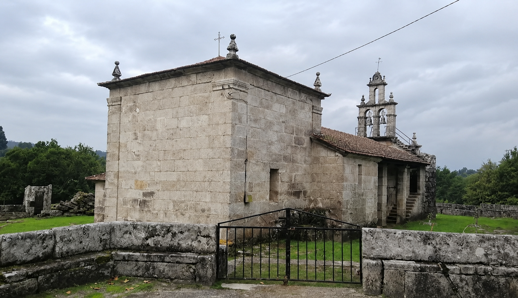 Vista da igrexa parroquial de Santa Mariña desde o adro, coa cabeceira, a nave e a espadana ao fondo.