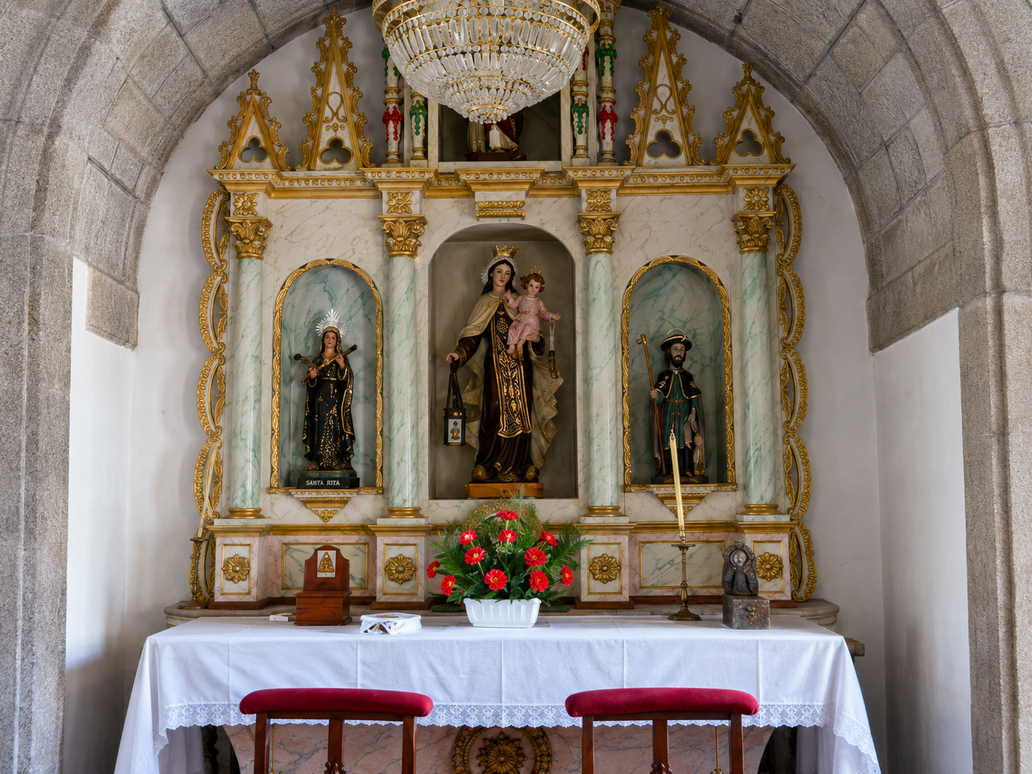 Altar lateral de la iglesia de Santa María de Paraños, presidido por la Virgen del Carmen y acompañado por las imágenes de Santa Rita y San Roque, reflejo de algunas de las devociones más arraigadas en la parroquia.