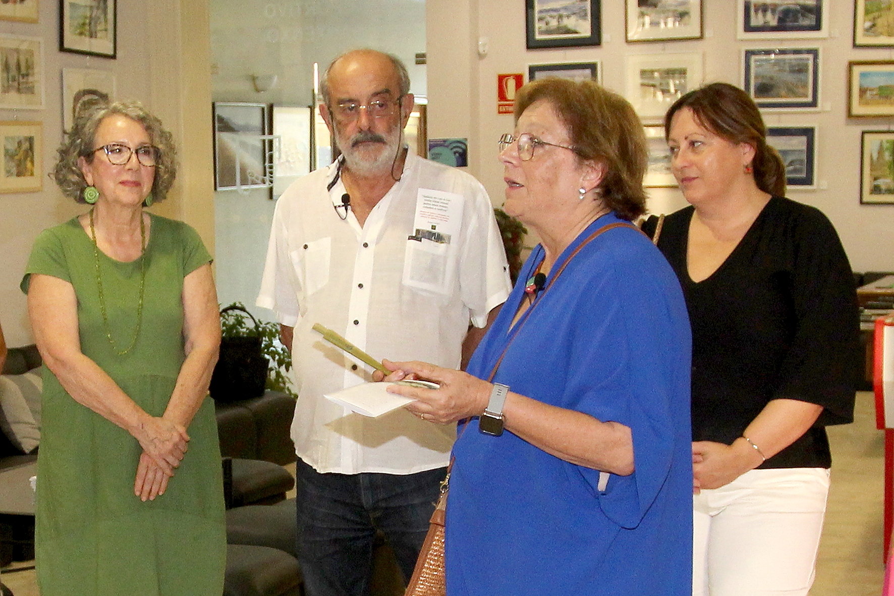 Ana Cancela, en representación del Grupo LUCET, interviene durante la inauguración de la exposición "Galicia en Luz y Color" en La Cultural de Sanxenxo, acompañada por varios de los participantes en la muestra.